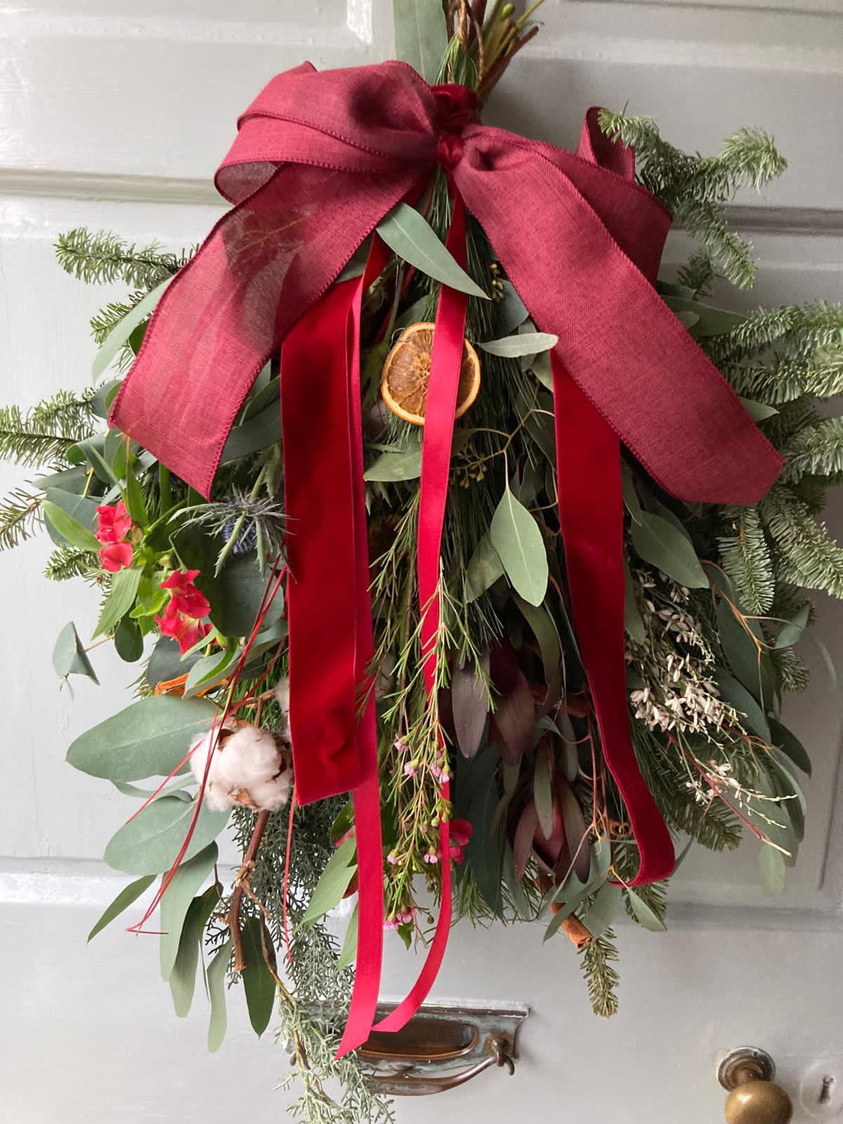 Close-up of Christmas swag showing pinecones, dried oranges, and cinnamon sticks – Barns Florals