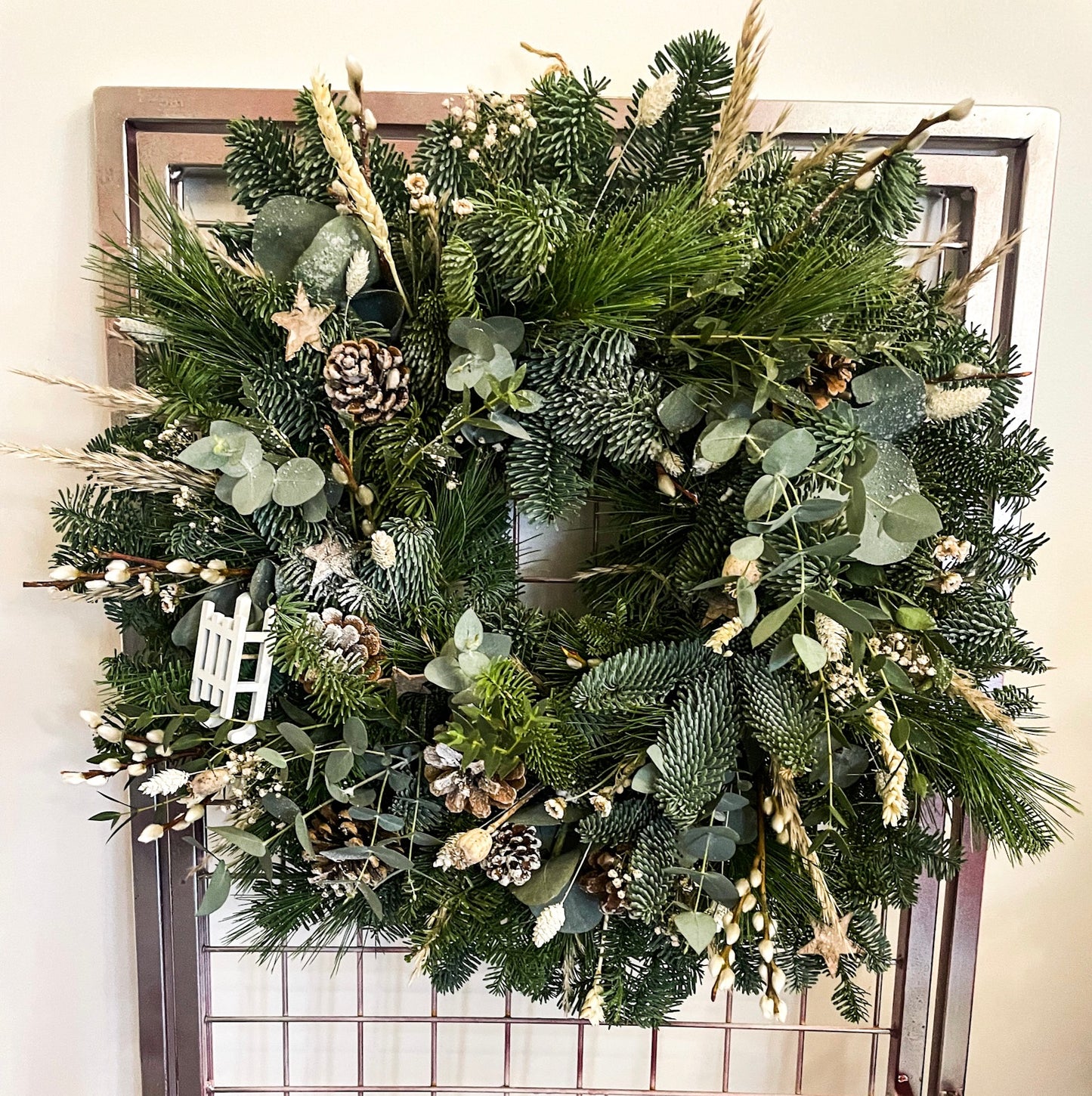 Close-up of Snow Queen & Pine Wreath showing poppy heads, pinecones, and willow texture – Barns Florals.